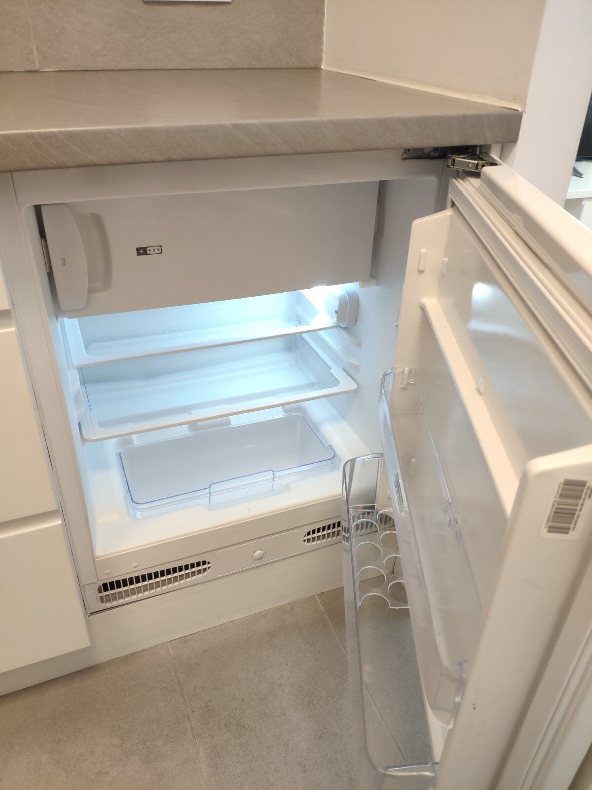 An open refrigerator with two shelves and a freezer compartment.