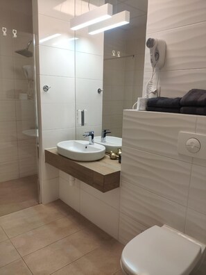 A modern bathroom with a glass-enclosed shower, a sink with a mirror, and a toilet. - Apartamenty Varsovia 304 (Warsaw)
