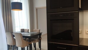 A modern kitchen with a built-in oven and a dining area with a table and chairs. - Apartamenty Varsovia 304 (Warsaw)