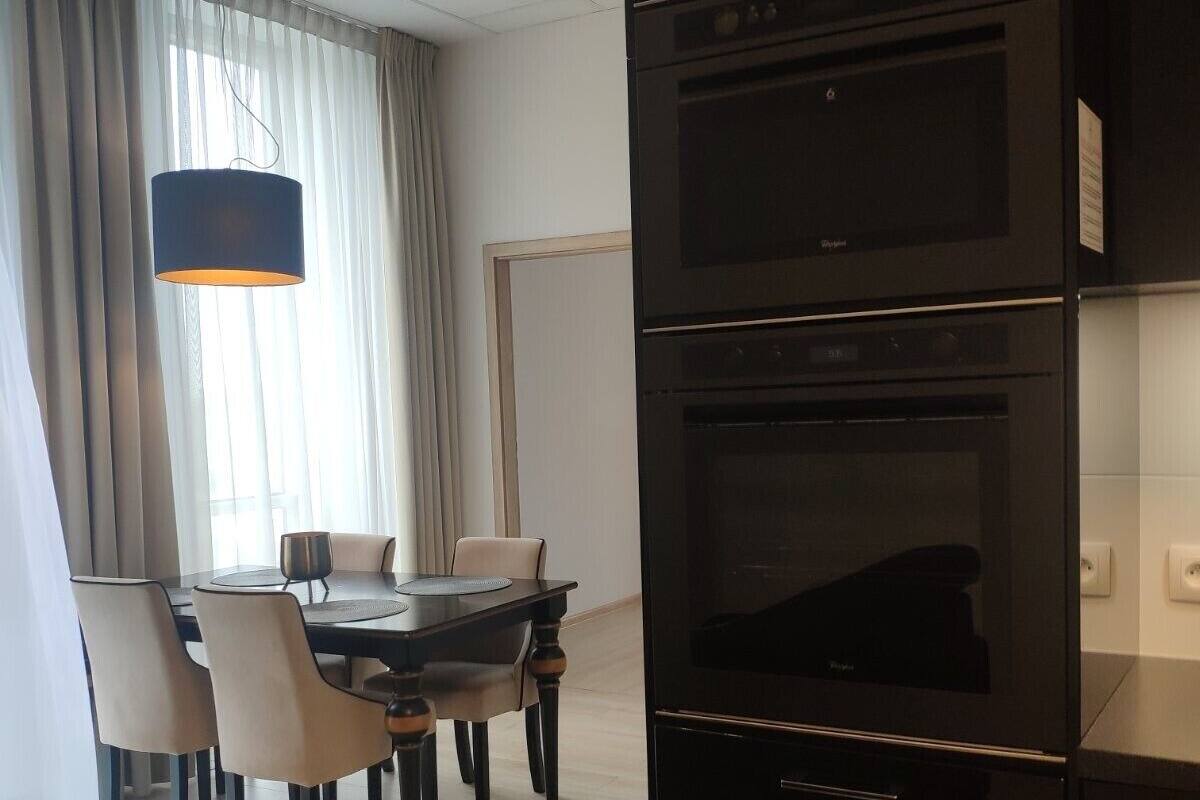 A modern kitchen with a built-in oven and a dining area with a table and chairs.