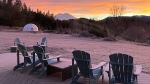 A wooden deck with four Adirondack chairs and a small table, overlooking a snowy landscape with a tent and a mountain in the background. - Charming 2BR Farmhouse Amazing View of Mt. Rainier - Family Friendly + Game Barn (Mineral)