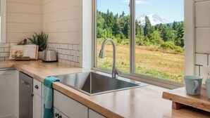 A kitchen with a large window, a sink, and a wooden countertop. - Charming 2BR Farmhouse Amazing View of Mt. Rainier - Family Friendly + Game Barn (Mineral)