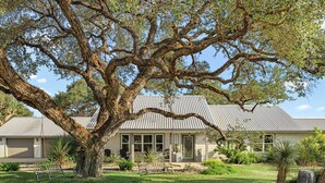 Une maison avec un grand arbre dans le jardin, une balançoire et un espace patio.