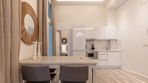 Una cocina moderna con armarios blancos, encimera de mármol y horno integrado.