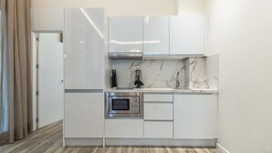 Una cocina compacta con armarios blancos, horno empotrado y salpicadero de mármol.