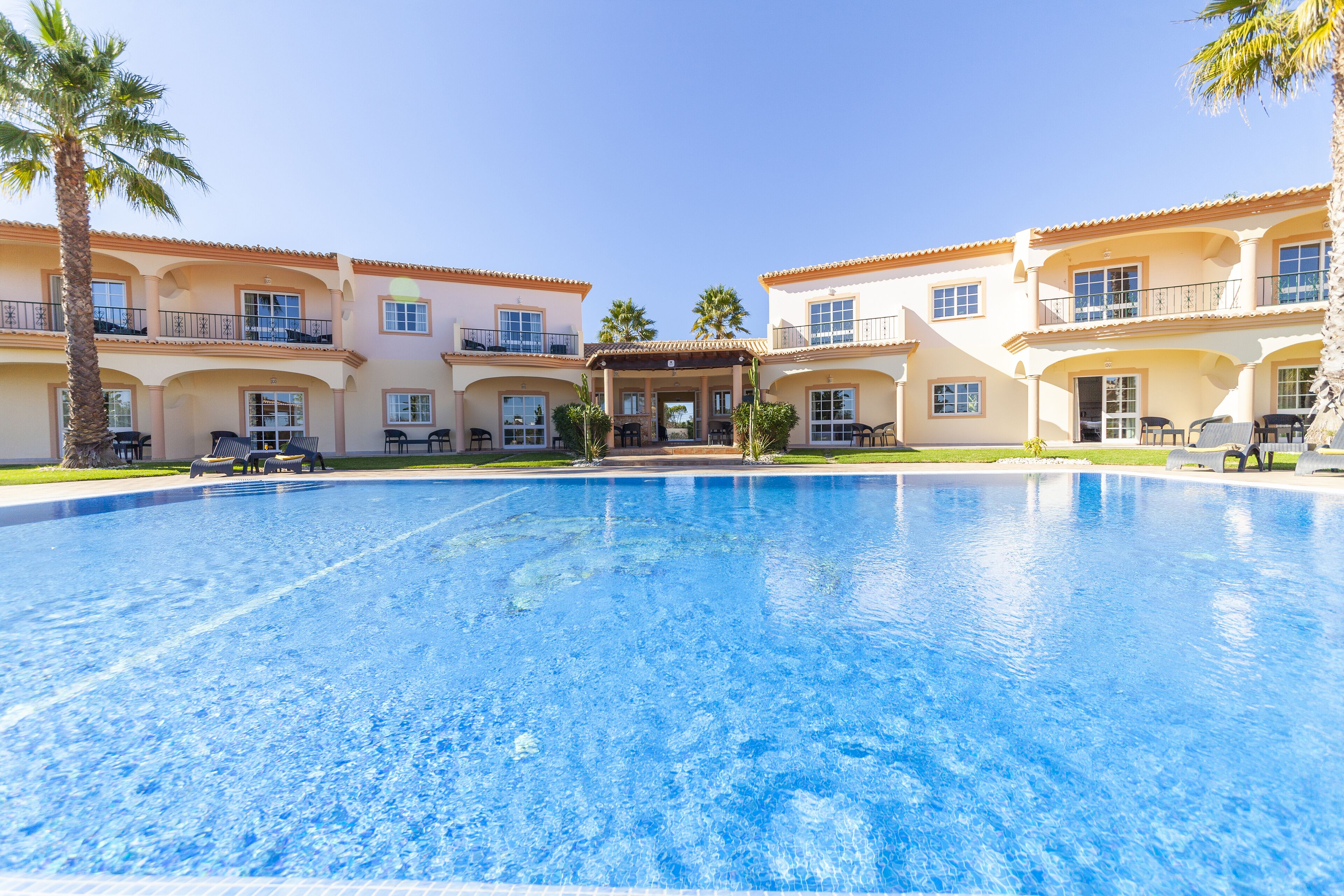 Una grande piscina con una veranda coperta di fronte a un edificio a più piani con balconi.