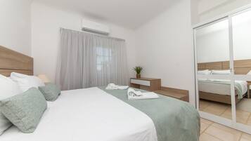 A hotel room with a bed, a bedside table, a mirror, and a sliding door.
