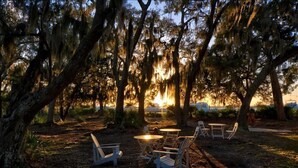 An outdoor seating area with tables and chairs, surrounded by trees with Spanish moss. - Escape to The Moorings #42 (Jekyll Island)