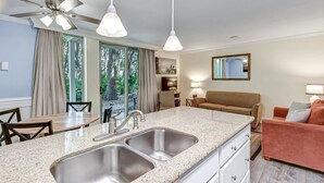 Uma cozinha moderna com bancada de granito, pia de aço inoxidável e ventilador de teto.
