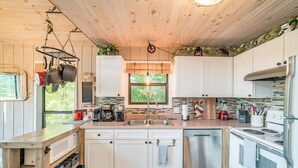 A modern kitchen with white cabinets, stainless steel appliances, and a wooden ceiling. - Canopy Ridge Retreat Cabin, couples oasis. Nature weddings (Sevierville)