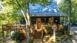 A rustic cabin with a wooden deck, a covered porch, and a small garden area. - Canopy Ridge Retreat Cabin, couples oasis. Nature weddings (Sevierville)