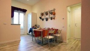 A dining area with a table set for four, a wall-mounted pot rack, and a window with curtains. - BandBFirenze 8Cittadella8 (Florence)