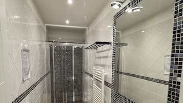 Une salle de bain moderne avec une douche à parois de verre, un lavabo blanc et un grand miroir.