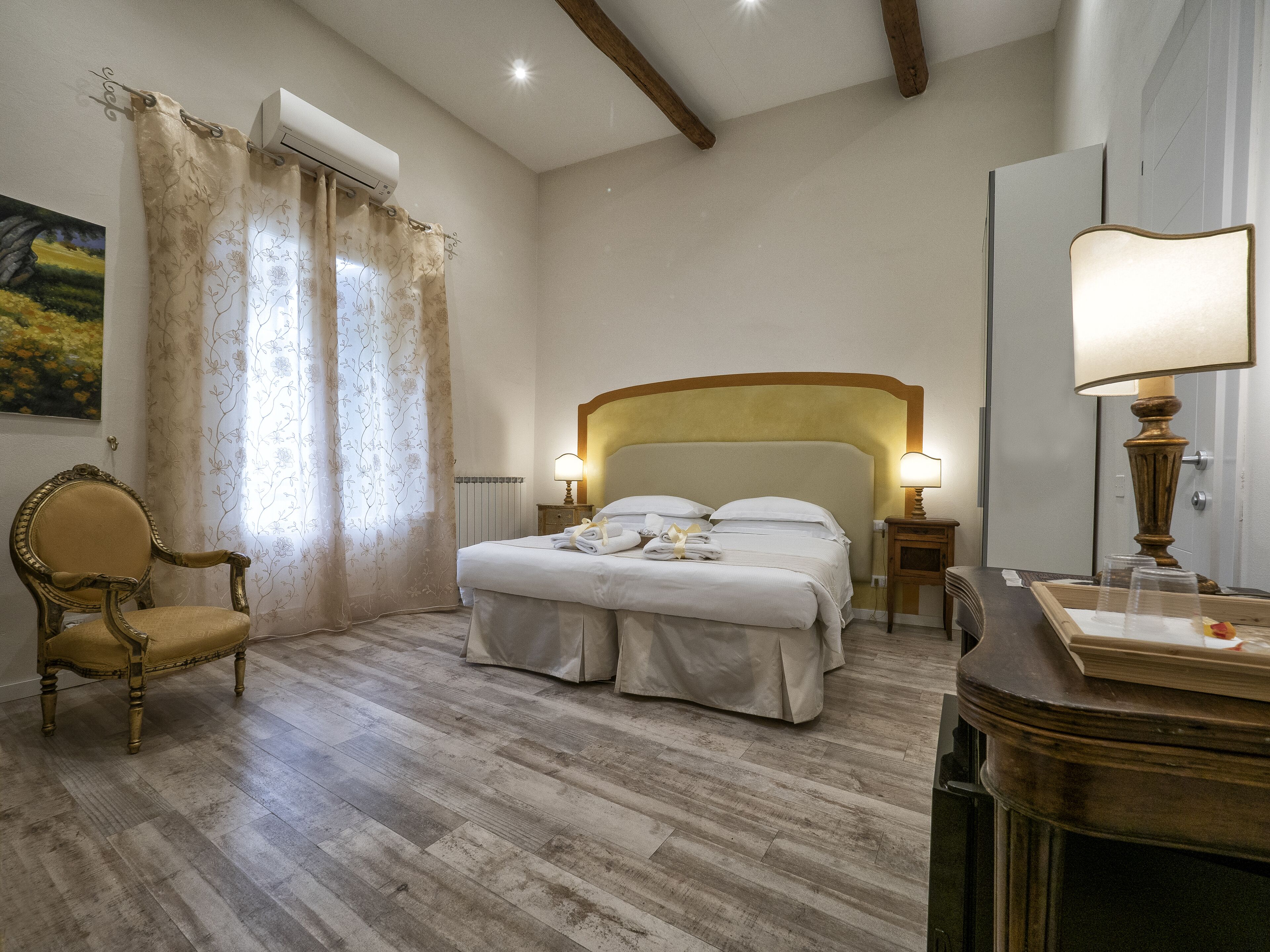 A hotel room with a bed, a chair, a lamp, and a radiator.