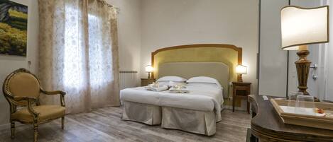 A hotel room with a bed, a chair, a lamp, and a radiator.