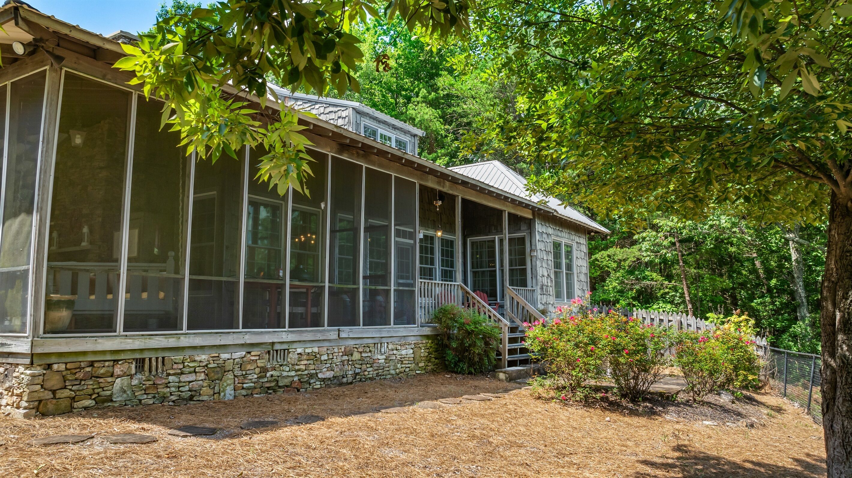 Una casa rustica con ampie finestre, fondamenta in pietra e un portico in legno.