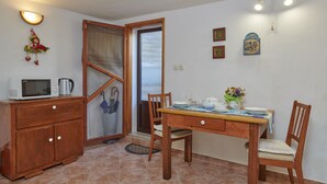 A dining area with a wooden table, chairs, a microwave, and a coffee maker on a cabinet. - Nice apartment for 2 people, 3 stars, 5 minutes to the beach (Ližnjan)