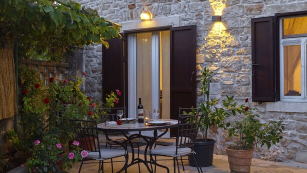 An outdoor dining area with a stone wall, a table with chairs, and potted plants. - Nice apartment for 2 people, 3 stars, 5 minutes to the beach (Ližnjan)