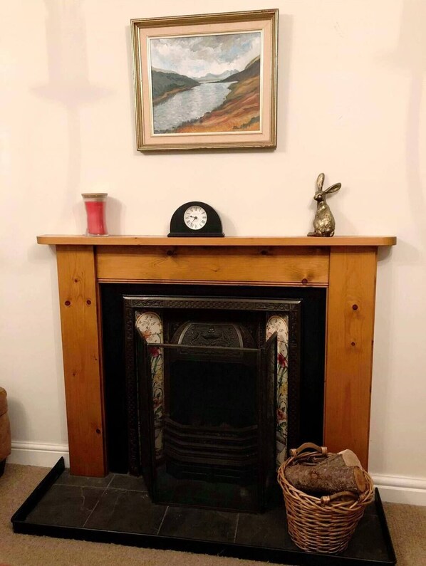 A fireplace with a mantel, a clock, and a framed painting above it.