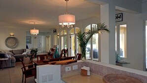 A spacious living area with a dining table, chairs, and a kitchen counter. There are pendant lights, a large window, and a potted plant. - "Atlantique" is a seaside space to be remembered! (Lowlands)