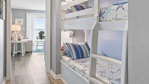A children's bunk bed with a starfish-themed mattress, a desk with a lamp, and a view of the outdoors. - Beachside Escape: Pool, Balcony, Free Chairs & More (Panama City Beach)