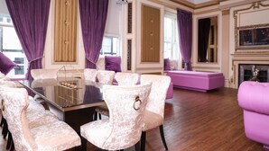 A dining area with a glass-top table, white upholstered chairs, and purple curtains. - Signature Living Bold Street Apartments (Liverpool)
