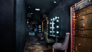 A dimly lit hallway with a mirror vanity, a plush armchair, and a small table with a chair. - Signature Living Bold Street Apartments (Liverpool)