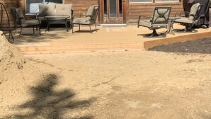 Une maison en bois à deux étages, dotée d’un patio couvert.
