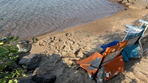 Une plage avec une eau cristalline, un rivage sablonneux et deux chaises de plage.