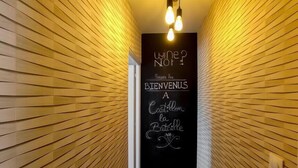 Un couloir étroit aux murs lambrissés, sur lequel est accroché un panneau noir avec une inscription blanche.