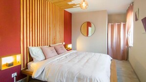 Une chambre moderne avec un lit, des lattes en bois, un miroir rond et un luminaire suspendu.