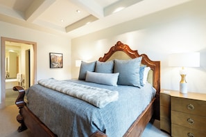 Een slaapkamer met een groot bed, een houten hoofdbord en een nachtkastje met een lamp.