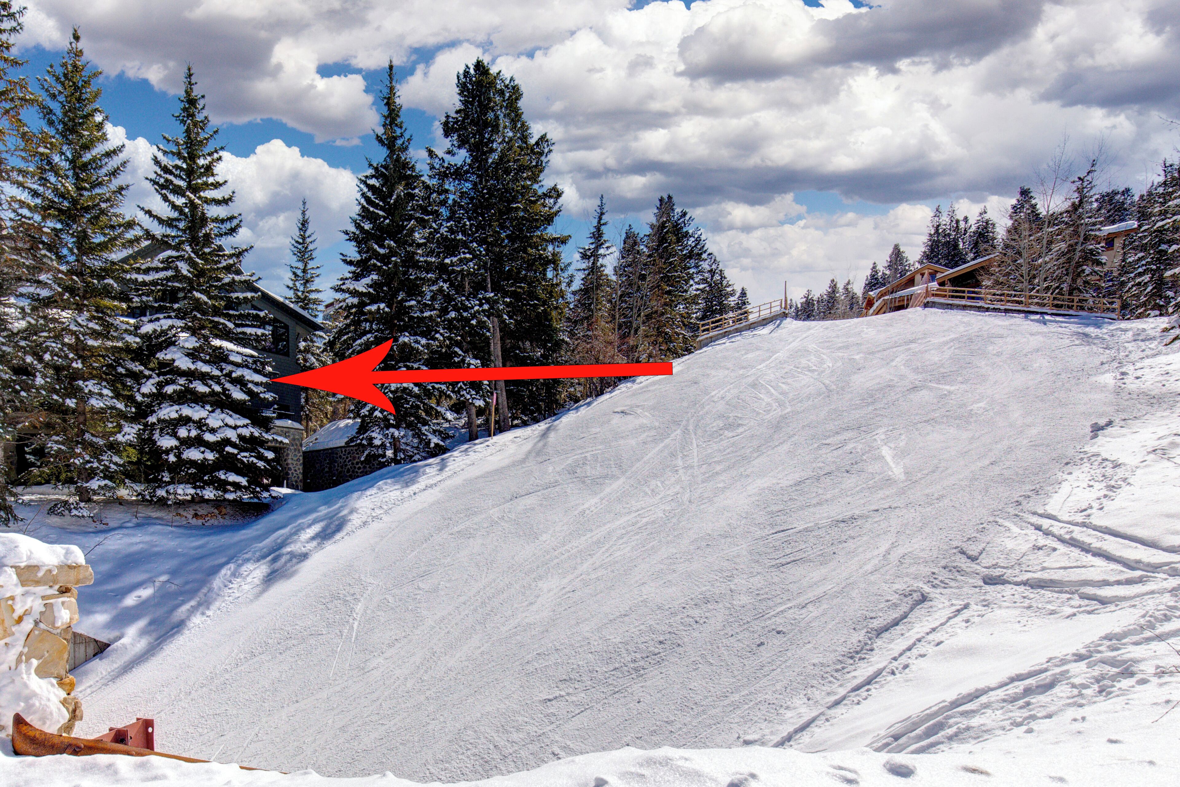 Ein verschneiter Skipisten mit Holzzaun und schneebedeckten Bäumen.
