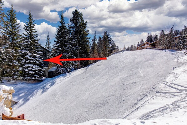A snowy ski slope with a wooden fence and snow-covered trees.
