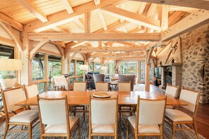 A spacious wooden dining area with a high ceiling and large windows.