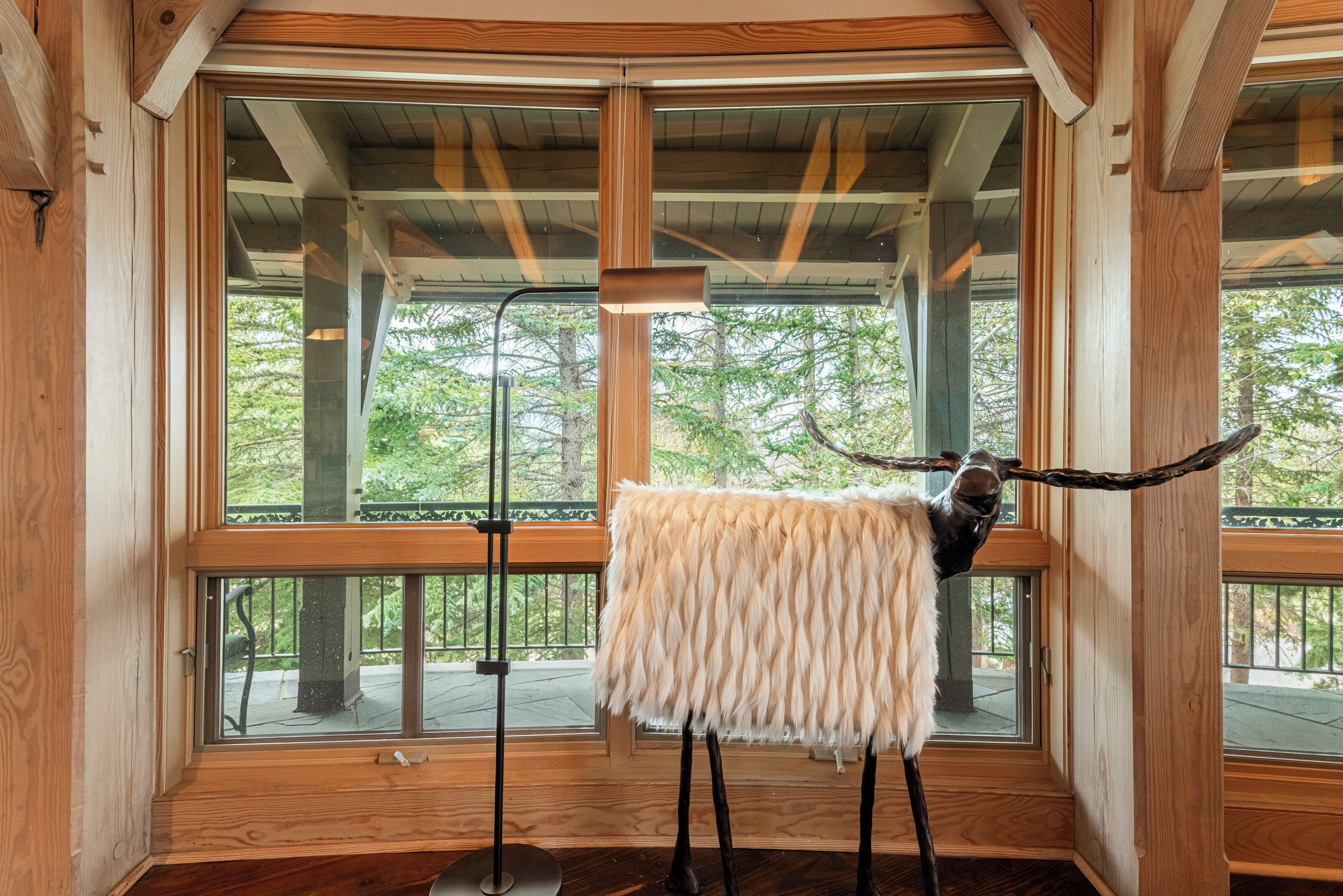 A room with wooden beams, a large window, and a mounted animal head.