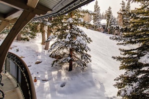A snow-covered ski slope with trees and a building in the background.