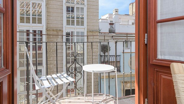 A balcony with a white table and chairs, a metal railing, and a view of neighboring buildings. - Zabalza- Holiday rental in Malaga (Málaga)
