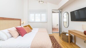 A bedroom with a bed, bedside table, TV, and a view of the outside. - Zabalza- Holiday rental in Malaga (Málaga)