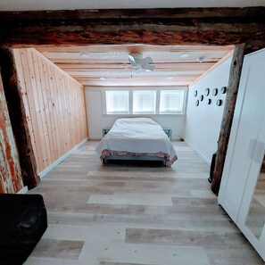 A bedroom with a sloped ceiling, a bed, a ceiling fan, and a window with blinds. - **Minimalist Mtn Living- Pets Welcome (30+ Days)** (Fairplay)