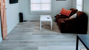 A room with a brown sofa, a white coffee table, a TV mounted on the wall, and a window with blinds. - **Minimalist Mtn Living- Pets Welcome (30+ Days)** (Fairplay)