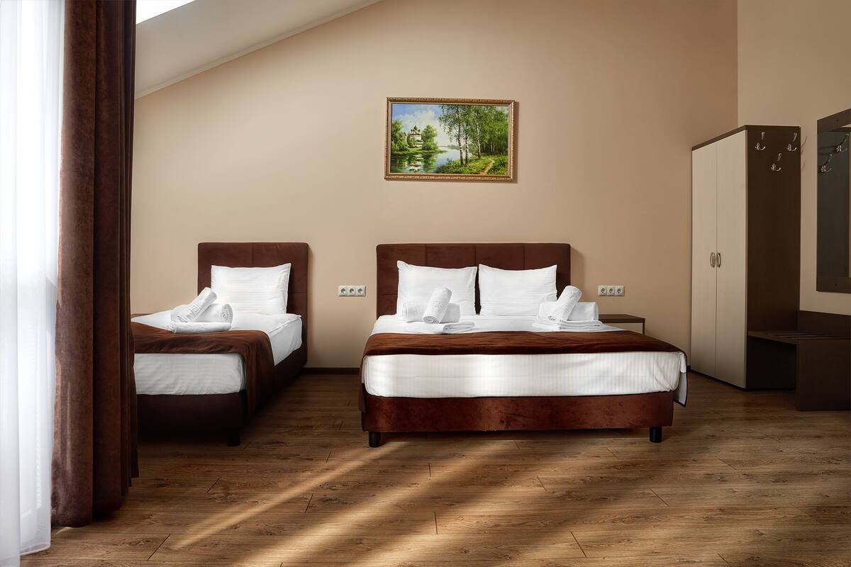 Quarto de hotel com duas camas, um quadro na parede e um guarda-roupa.