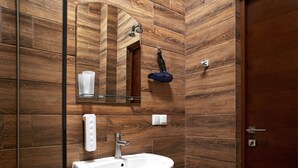 A bathroom with a wooden wall design, a white sink, a mirror, and a towel rack.