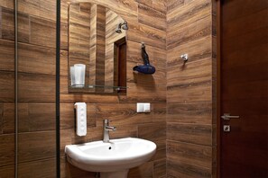 A bathroom with a wooden wall design, a white sink, a mirror, and a towel rack.