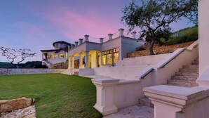 A large, modern house with a well-maintained lawn, a stone staircase, and a view of the surrounding landscape. - Austin Guitar Pool | 87.5 FT Guitar Pool (Austin)