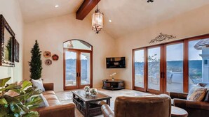 A spacious living room with a fireplace, leather sofas, a coffee table, and large windows offering a mountain view. - Austin Guitar Pool | 87.5 FT Guitar Pool (Austin)