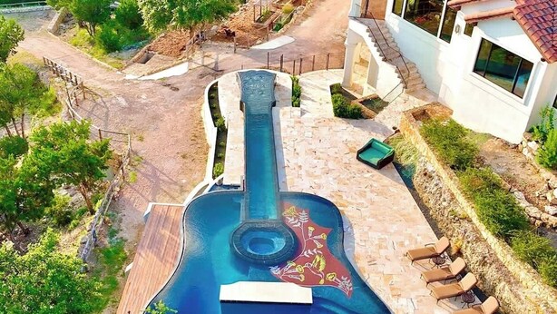A pool shaped like a guitar with lounge chairs and a staircase leading to a building. - Austin Guitar Pool | 87.5 FT Guitar Pool (Austin)