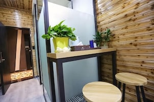 A small room with a wooden wall, a table with two stools, and a potted plant on the table.