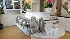 A buffet setup with various food dispensers and stacked plates. - Feitian Hotel (Jingyuan)