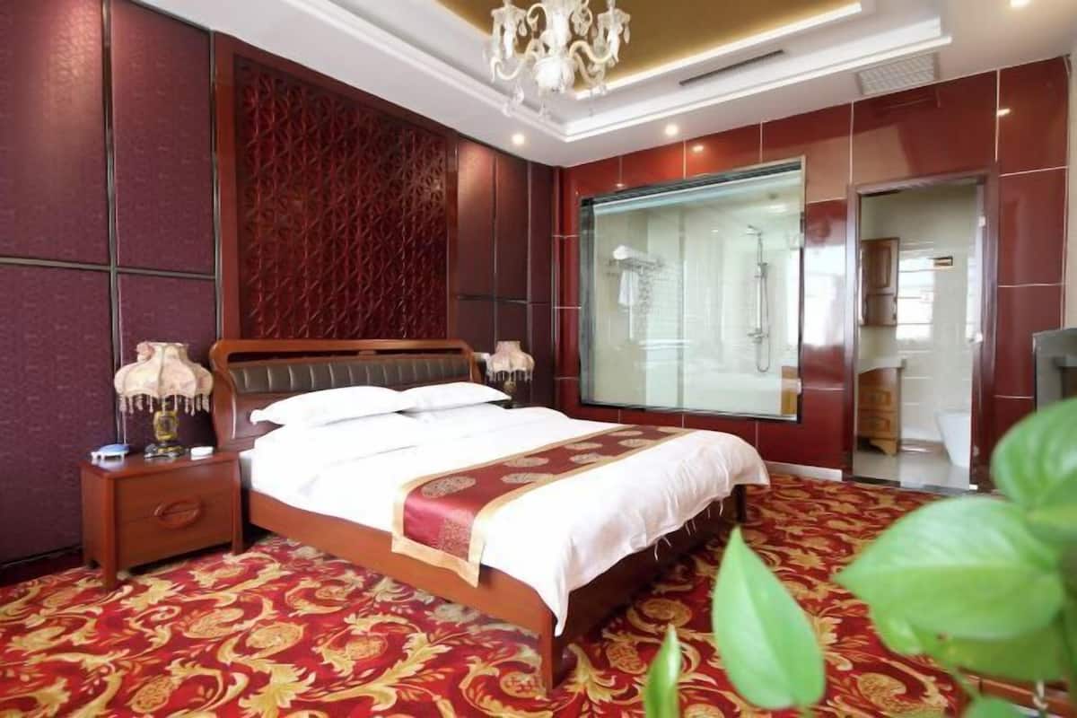 Habitación de hotel con una cama grande, una mesita de noche, un espejo y zona de ducha.